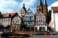 a row of buildings with towers on each side and cars parked in the street next to them