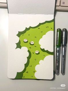 two pens sitting on top of a notebook next to a green and white christmas tree