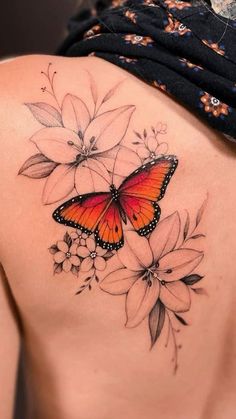 a woman's back with a butterfly and flowers tattoo on her left side shoulder