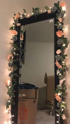 a mirror that has flowers on it and some lights in the reflection, next to a cardboard box