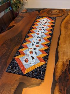 A one of a kind Halloween table runner that is a definite show stopper.  Either side of this handmade table topper will give added flair and moody color to your fall decorating. This quilted runner is made with a spooktacular focal fabric featuring pumpkins, ghosts, tombstones, witchy items, and more, and is coordinated with rusty fall orange, golden sunset yellow, and a fun black paint speckled fabric.  The reverse side shows off a burnt orange moon fabric. 80/20 cotton-poly batting was used giving this table topper a subtle softness and crinkle.  The quilted design is an all over spiderweb pattern in a light grey polyester thread. Measurements for the runner are 11.5" x 41" making it a great size for most tables, counters, dressers, or sideboards.  The final runner was washed in scent an Quilted Halloween Table Runners, Candy Corn Quilted Table Runner, Halloween Quilt Table Runner, Witchy Items, Table Runner Halloween, All Hallows Eve Quilt, Moon Fabric, Table Runner Quilted, Halloween Table Runner