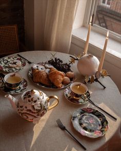 the table is set with tea, croissants and coffee cups on it