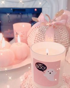 there is a candle on the table next to other candles and decorating items that are pink