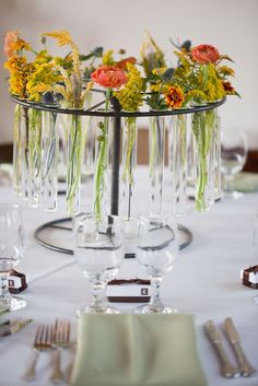 there are many flowers in the vases on this table clothed place setting with silverware