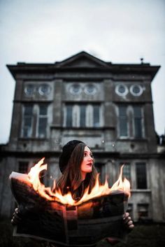 a woman holding a newspaper with fire in front of her