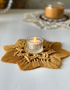 a small candle sitting on top of a table next to a doily shaped like a flower