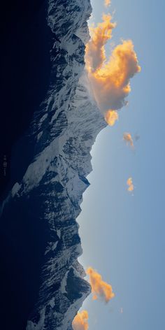 some clouds are in the sky and one is on top of a mountain with snow