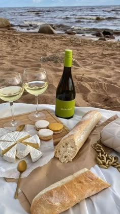 wine, cheese and bread sit on a table at the beach