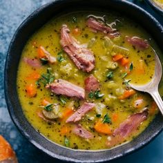 a bowl of soup with ham, carrots and parsley in it next to some bread