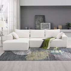 a living room with a white couch and rug on the floor in front of a gray wall