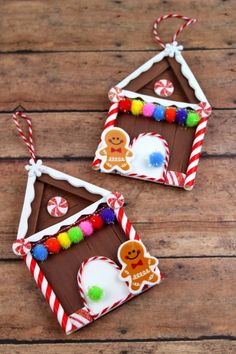 two gingerbread house ornament hanging on a wooden table with candy canes