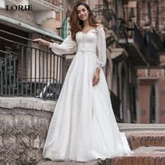 a woman in a white wedding dress standing on steps with her arms out to the side