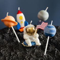 three small toy rockets sitting next to each other on a black surface with an american flag