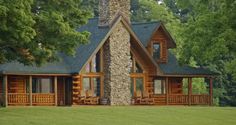 a log cabin sits in the middle of a grassy field with trees and grass around it