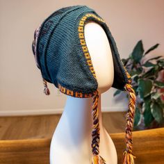 a mannequin head wearing a knitted hat on top of a wooden table