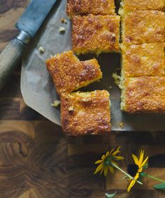 slices of cake sitting on top of a cutting board next to a knife and flowers