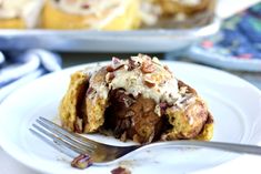 a piece of cinnamon roll on a plate with a fork in front of the rest of the pie