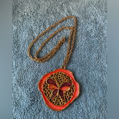 This Necklace Is From The 1960s New Old Stock Never Worn And Is Indicative Of The Jewelry Of The Time. An Orange Flower With Gold In Sat And Inside The Center Is An Orange And Purple Butterfly. One Of The Saints During That Arrow Was Butterflies Are Free. The Chain On The Necklace Is 24 Inches Long And Is Gold Metal. And The Medallion Is 2 1/2 Inches In Diameter And A Very Shiny Paint Was Used On It As It Is Extremely Attractive To The Eye. A Definite Flower Power Symbol. Vintage Orange Flower Jewelry, Orange Vintage Flower Jewelry, Retro Orange Necklace Gift, Retro Purple Jewelry For Gifts, Vintage Purple Flower-shaped Jewelry, Vintage Purple Flower Jewelry, Purple Pendant Necklace, Orange Necklace, Jade Crystal