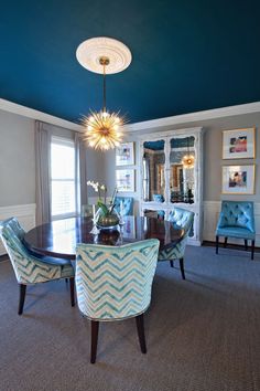 a dining room table with blue chairs and a chandelier hanging from the ceiling