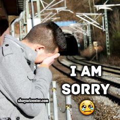 a man standing next to train tracks with the words i am sorry on it