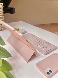 an apple keyboard and mouse on a table next to a cell phone with a pink cover