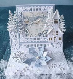 a card with snow on the ground and a house in the middle, surrounded by trees