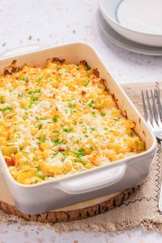 a casserole dish with cheese and vegetables in it on a place mat next to silverware