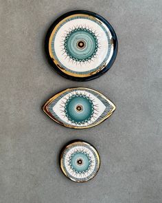 three plates sitting on top of a table next to each other, one with an eye design