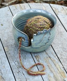 a yarn ball in a blue bowl on a wooden table with a string attached to it