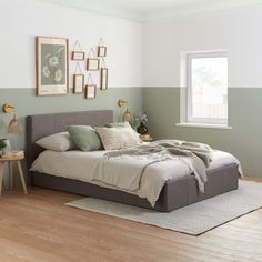 a bed sitting in a bedroom on top of a hard wood floor next to a window