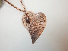 A totally unique stamped heart metal pendant. This metal heart is covered with random stamped hearts and adorned with tiny metal balls. To top it off, a metal or crystal bead is added to the top off the pendant. There are two color options - aluminum or copper. It is 24 inches long on lightweight chain. Metal Heart Necklace With Open Heart Shape, Metal Heart Necklace With Heart Beads, Metal Heart Necklace With Open Heart And Heart Beads, Metal Open Heart Necklace With Heart Beads, Bronze Heart Necklaces For Valentine's Day, Bronze Heart-shaped Necklace For Valentine's Day, Heart-shaped Silver Copper Jewelry, Silver Heart-shaped Copper Jewelry, Bronze Heart Necklaces For Jewelry Making