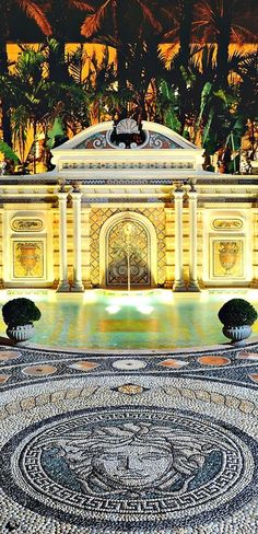 the entrance to an elaborately designed building in black and white with palm trees around it