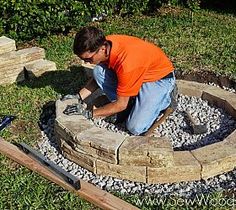 a man in an orange shirt working on a stone fire pit