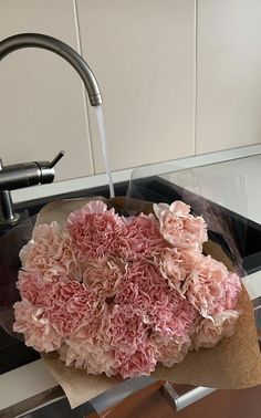 a bunch of pink flowers sitting on top of a sink under a faucet