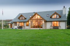 a house that is in the middle of a field with grass and trees around it