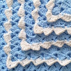 a blue and white crocheted blanket is laying on top of a tablecloth