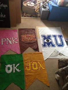 several banners are laid out on the floor in front of a chair and bookshelf