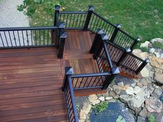 an overhead view of a wooden deck with black railings and handrails next to a pond