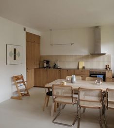 a table and chairs in a room with a stove on the far wall, an oven to the right