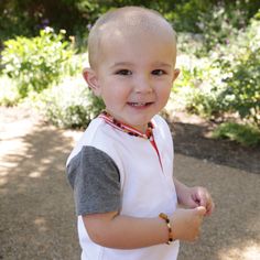 a little boy that is standing up with a smile on his face and wearing a white shirt