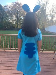 a girl wearing bunny ears standing on a deck with her back turned to the camera