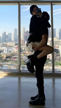 a man and woman standing in front of a window with the city skyline behind them