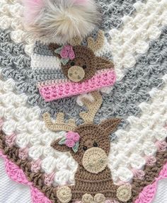 a crocheted blanket with two hats on top of it and a stuffed animal in the middle