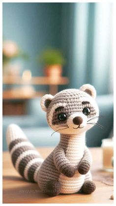 a crocheted raccoon sitting on top of a wooden table