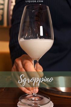 a person holding a wine glass with white liquid in it and the words scorpion written below