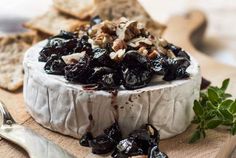 cheese with raisins and walnuts on a cutting board next to crackers