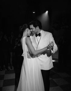 a man in a tuxedo and a woman in a gown dance on a checkered floor