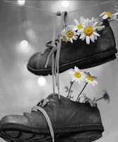 black and white photograph of shoes with daisies hanging from strings