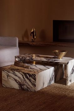 a marble coffee table sitting on top of a carpeted floor next to a white couch