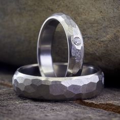 two wedding rings sitting next to each other on top of a stone slab with a diamond in the center